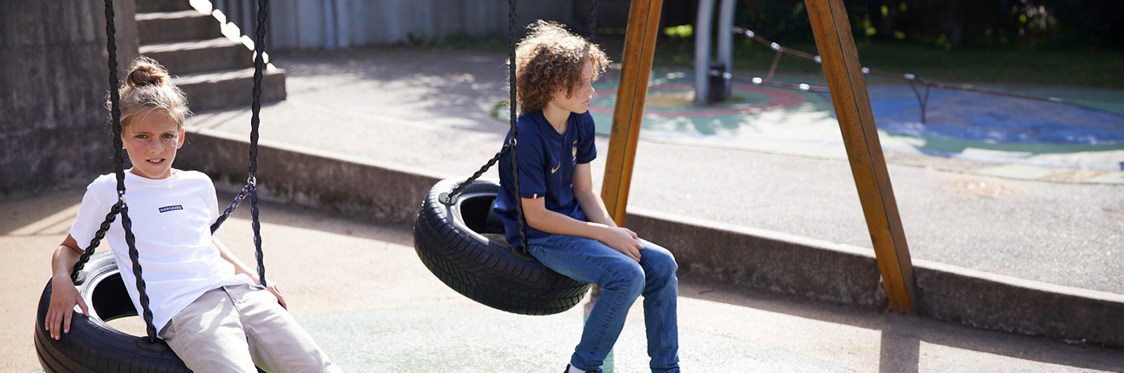 Young boys swing on a swing frame.